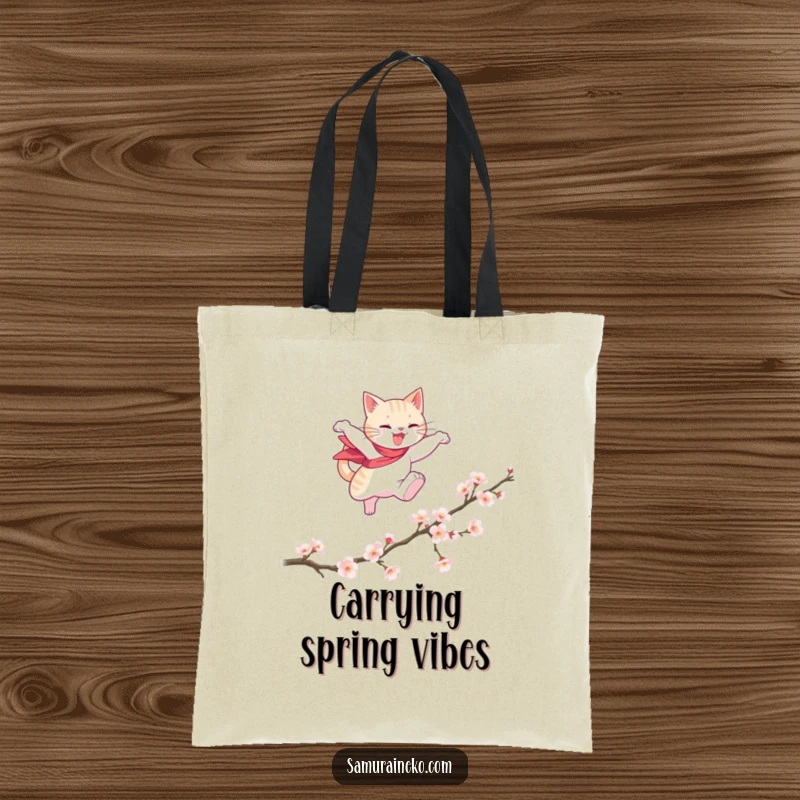 Funny tote bag featuring a cat hero gracefully leaping over a fallen cherry blossom branch, perfect for stylish, funny carrying.